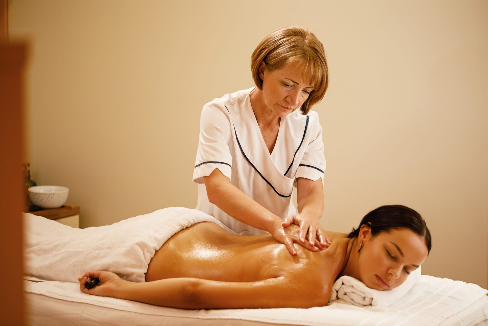 mujer joven con masaje de espalda por terapeuta femenina en el spa el foco esta en el terapeuta de masaje